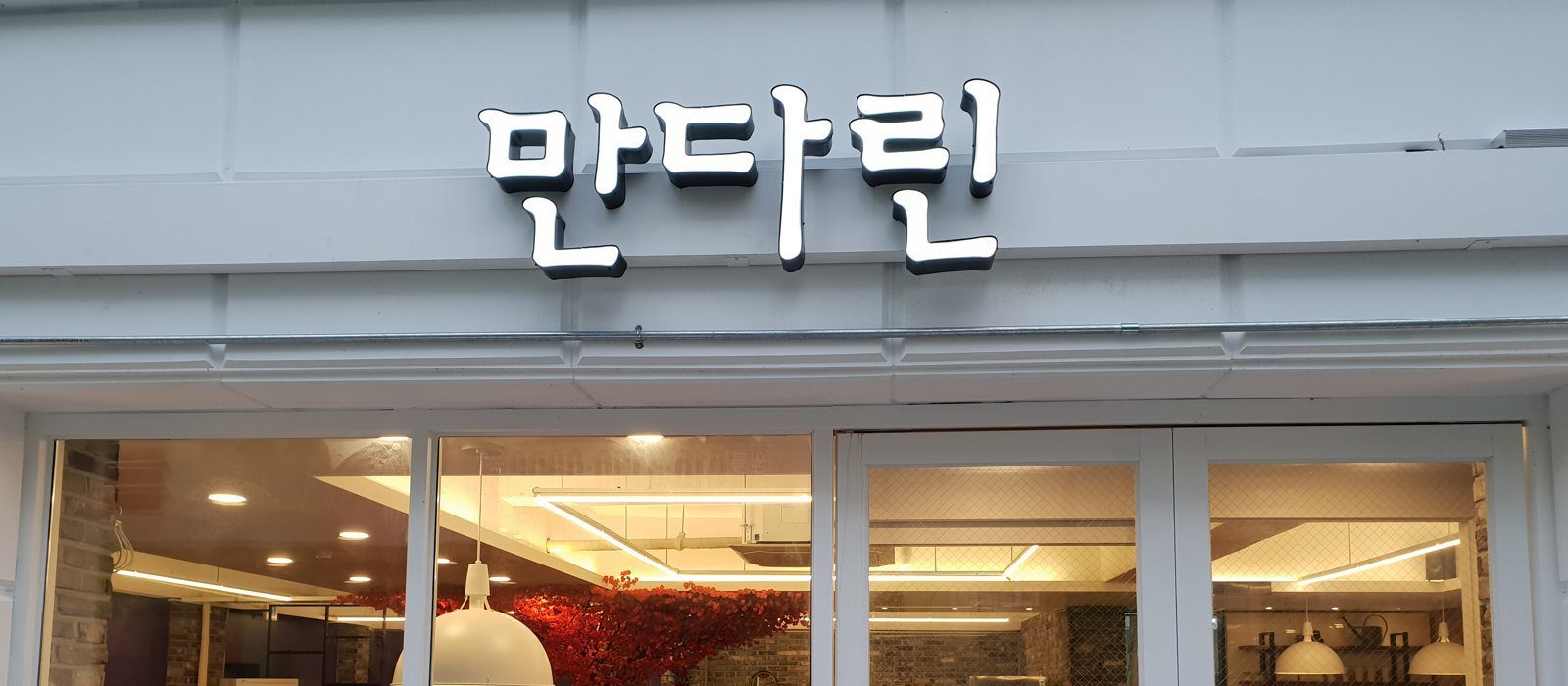 흰 외벽의 «만다린» 간판과 유리창 너머 홀